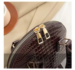 Detail of premium brown crocodile pattern leather handbag with golden dual zippers