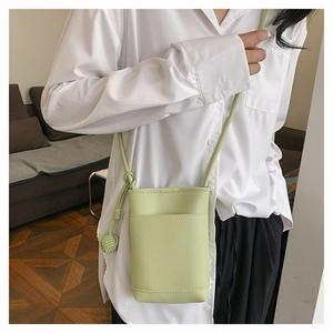 Détail du mini sac bandoulière vert clair en cuir grainé avec bandoulière à nœud déco