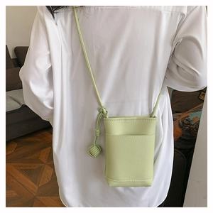 Mannequin portant un petit sac bandoulière vert clair en cuir grainé avec détail de nœud