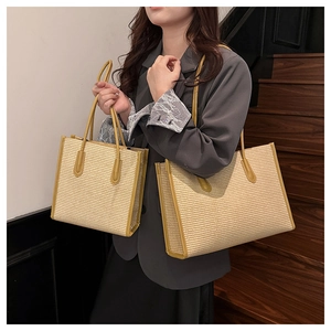 Detail of woven straw tote bag set with bright yellow leather trim in two sizes