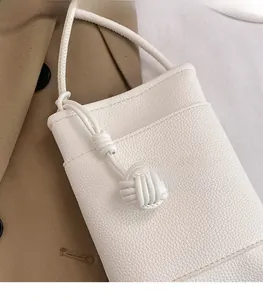 Gros plan du mini sac blanc en cuir grainé avec un détail de nœud tressé élégant