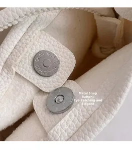 Détail macro de la boucle magnétique en métal sur le sac bandoulière en cuir grainé blanc