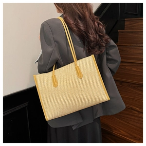 Detail of stylish woven straw tote bag with bright yellow leather straps and trim