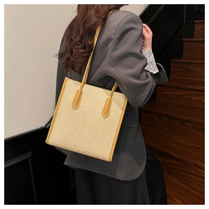 Detail view of woven tote bag with mustard yellow leather trim and long shoulder straps