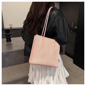 Detailed view of a large woven pink tote bag being worn over the shoulder by a model