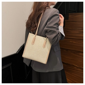 Detail of woven straw tote bag texture and leather strap in minimalist modern setting