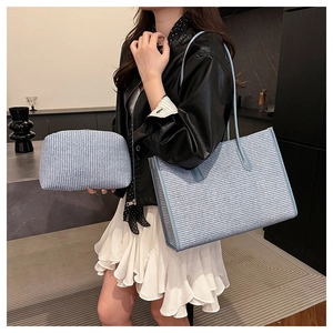 Close-up of blue woven texture tote bag and matching clutch set in modern interior setting