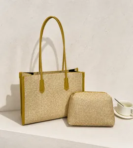 Detail of straw tote bag set with olive green leather handles and small inner pouch
