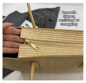 Detail shot of the smooth gold metal zipper closure on a straw woven tote bag