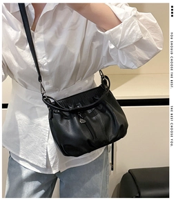 Detail of black cloud-shaped crossbody bag with heart pendant and pebbled texture