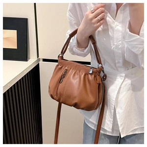 Detail of caramel pleated bucket bag showing premium lychee grain texture and metal zippers