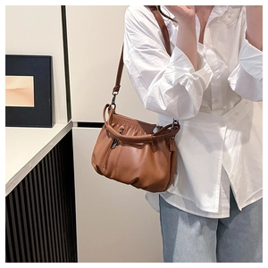 Detailed view of brown pleated crescent shoulder bag with adjustable strap and retro style