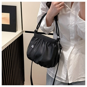 Detail of black pleated cloud bag showing lychee grain texture and thin handle