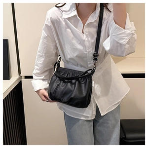 Detail of black pleated bucket bag in litchi grain leather with adjustable strap