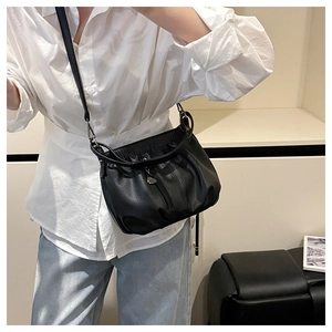 Black pleated faux leather bucket bag shown as a shoulder bag on a model in a studio