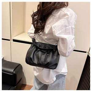Detail of black pleated crossbody bag with pebble leather texture on casual outfit