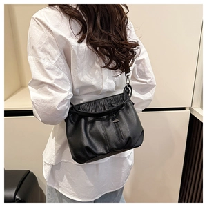 Detail view of black lychee grain leather crossbody bag with pleated texture on a model