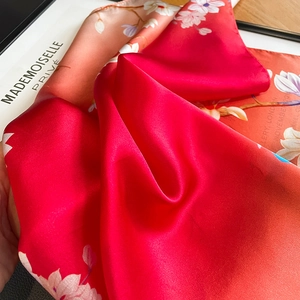 Silk scarf with red gradient and white floral pattern showing soft satin texture