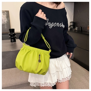 Close-up of vibrant lime green pleated shoulder bag featuring decorative zipper and metal charm