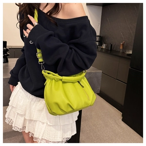 Detail of lime green crossbody bag featuring ruched pebble leather and slim shoulder strap