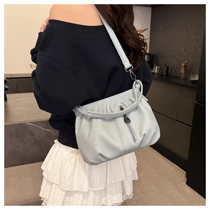 Close-up of light blue pleated bucket bag featuring lychee grain leather and zipper detail