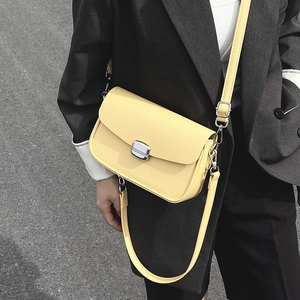 Minimalist bright yellow lychee leather saddle bag with silver buckle worn by a model