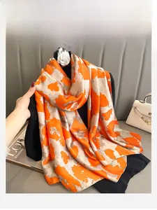 Detail of silk-feel scarf featuring bright orange and beige abstract color blocks