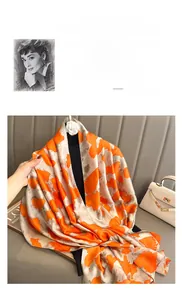 Detail of silk scarf with orange and grey abstract pattern and camellia flower brooch