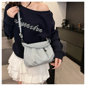 Detail of light blue lychee leather bucket bag with pleated top and metal zipper tassel