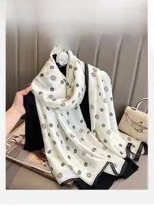 Detail of silk-like scarf with camellia print and black border on a cream background