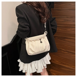 Detail of cream white pleated shoulder bag with textured leather and metal pendant accent