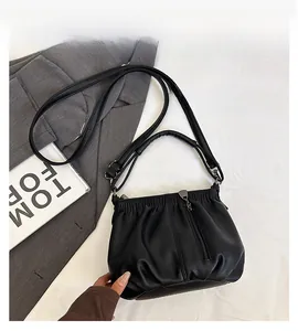Close-up of black lychee texture leather bucket bag with pleated design and metal tassel