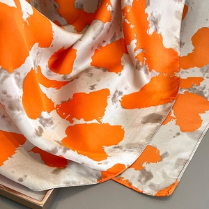 Silk-textured shawl with orange and taupe abstract print shown in a natural drape