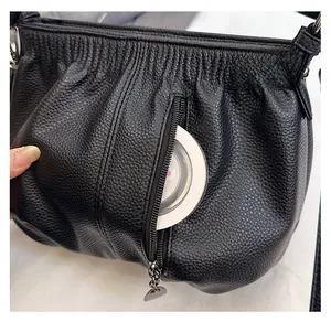 Detail of the front vertical zipper pocket on black lychee grain faux leather handbag