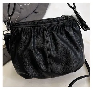 Detail of black lychee texture leather handbag with drawstring closure and silver buckles
