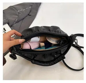 Top view of spacious interior of black pleated shoulder bag with cosmetics inside