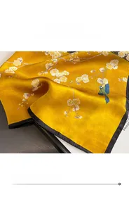 Close-up of a silk scarf showing floral print with kingfisher bird and fine hem detail