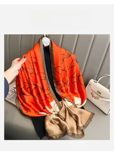 Detailed view of silk scarf with orange and brown floral print and fine stitched edges