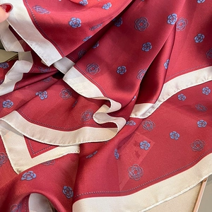 Close-up of luxury wine red satin silk scarf with camellia patterns and cream borders