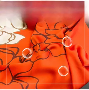 Detail of silk-like orange scarf showing glossy texture and elegant peony flower print