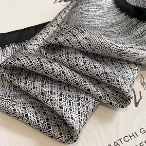 Vue détaillée d'un foulard carré en soie avec motif géométrique noir et blanc élégant