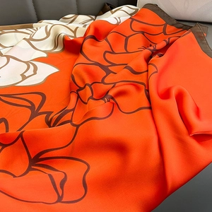 Elegant floral print silk scarf in orange and cream with a premium satin finish and drape