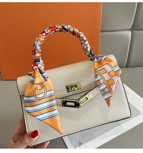 Close-up of litchi grain beige handbag handle wrapped in decorative plaid silk ribbon
