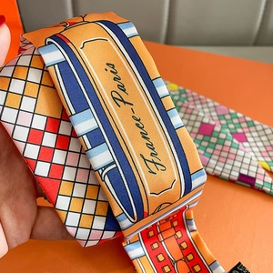 Detailed macro view of high-quality silk twilly scarf with geometric patterns and cursive text