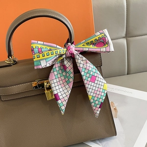 Brown leather handbag with colorful geometric print silk scarf tied as a bow on handle