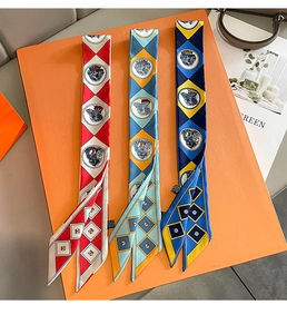Detailed view of three twilly scarves with dog patterns and diagonal stripes in a gift box