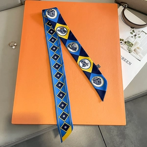 Close-up of patterned silk twilly scarf neatly displayed on an orange luxury gift box