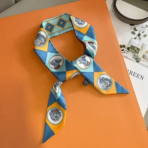 Narrow silk twilly scarf with geometric patterns on an orange gift box background