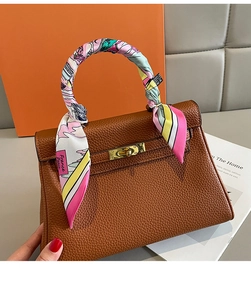 Détail d'un foulard en soie enroulé sur la poignée d'un sac en cuir marron avec fermoir doré