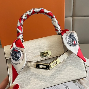 Beige lychee leather handbag with printed silk scarf wrapped handle on orange gift box
